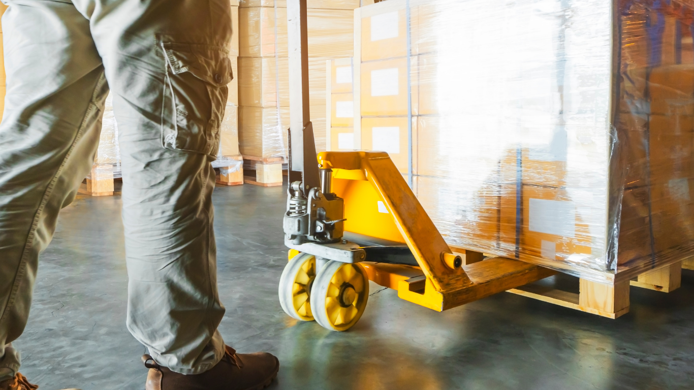 Warehouse worker moving a hand pallet truck along a racking aisle