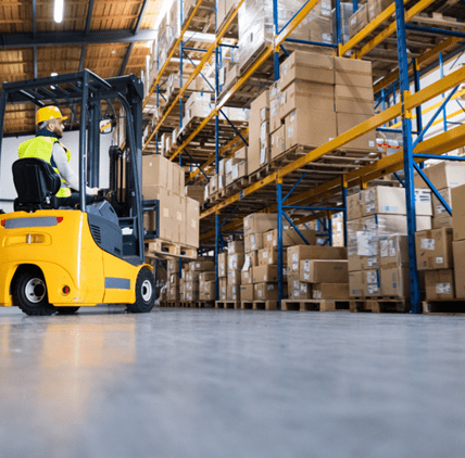 Forklift moving pallets down an aisle in a B2C fulfillment warehouse