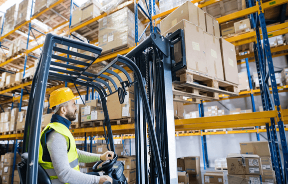 Warehouse worker in a hard hat checking stock on high racking
