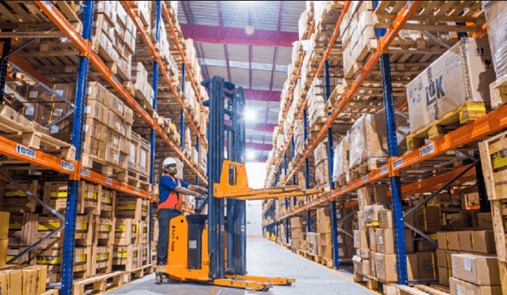 Order picker lifting a pallet in a narrow aisle between tall warehouse racking